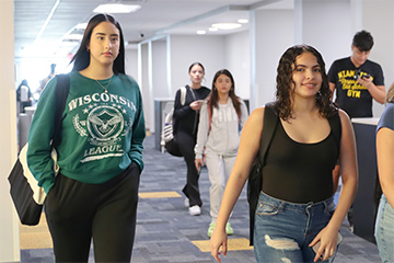 Three students walking down a hallway at a campus
