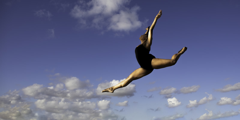 Dancer leaps with the sky in the background