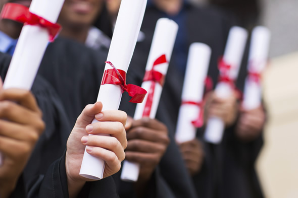 students in graduation robes holding diplomas