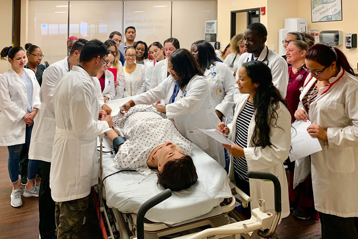 A professor demonstrates proper procedures during a class with a human patient simulator