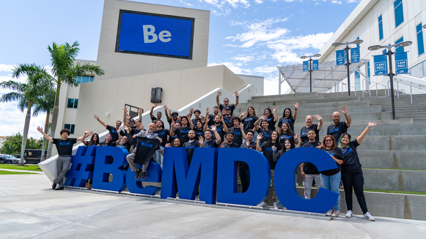 Students standing in fron of a Be MDC sign