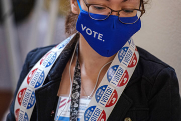 A closeup photo of a woman wearing a protective mask participating in the voting process