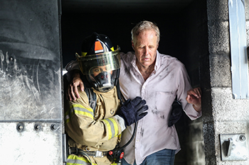 Simulation involving a firefighter helping a civilian out of a burning facility