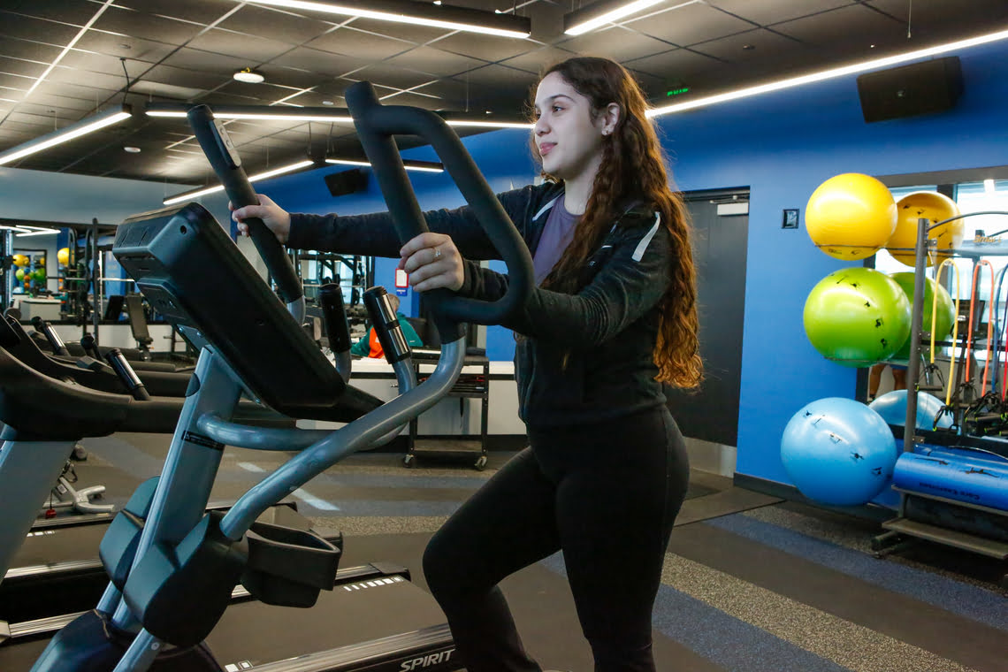 Young woman using an elliptical machine in a gym