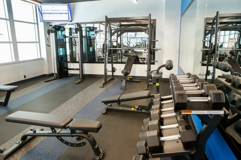 Gym with free weights, benches, and strength training equipment.