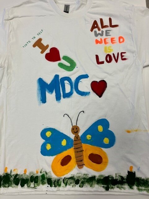white tee shirt with the words 'all we need is love' hand painted on it
