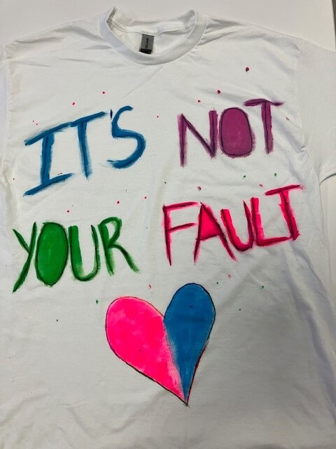 white tee shirt with the words 'it's not your fault' hand painted on it