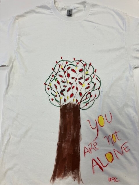 white tee shirt with the words 'you are not alone' hand painted on it