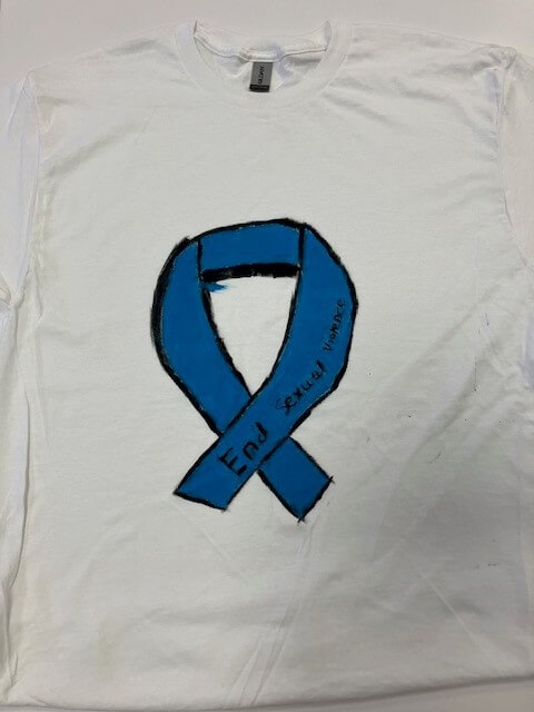 white tee shirt with the words 'end sexual violence' on a blue ribbon hand painted on it