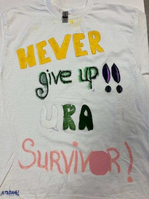 white tee shirt with the words 'never give up!! u r a survivor!' hand painted on it