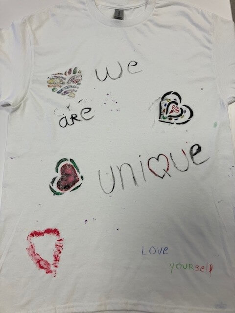 white tee shirt with the words 'we are unique. love yourself' and many hearts hand painted on it